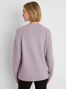 Back view: Lavender fuzzy sweater with ribbed mock neck and decorative eyelets along the raglan shoulders.