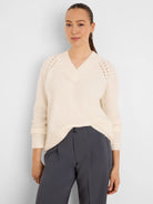 Cream, fuzzy V-neck sweater with raglan eyelet shoulder details and ribbed cuffs.