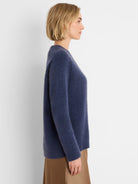 Side view of a model wearing a navy blue soft, brushed sweater with a relaxed fit. Ribbed cuffs and hem.