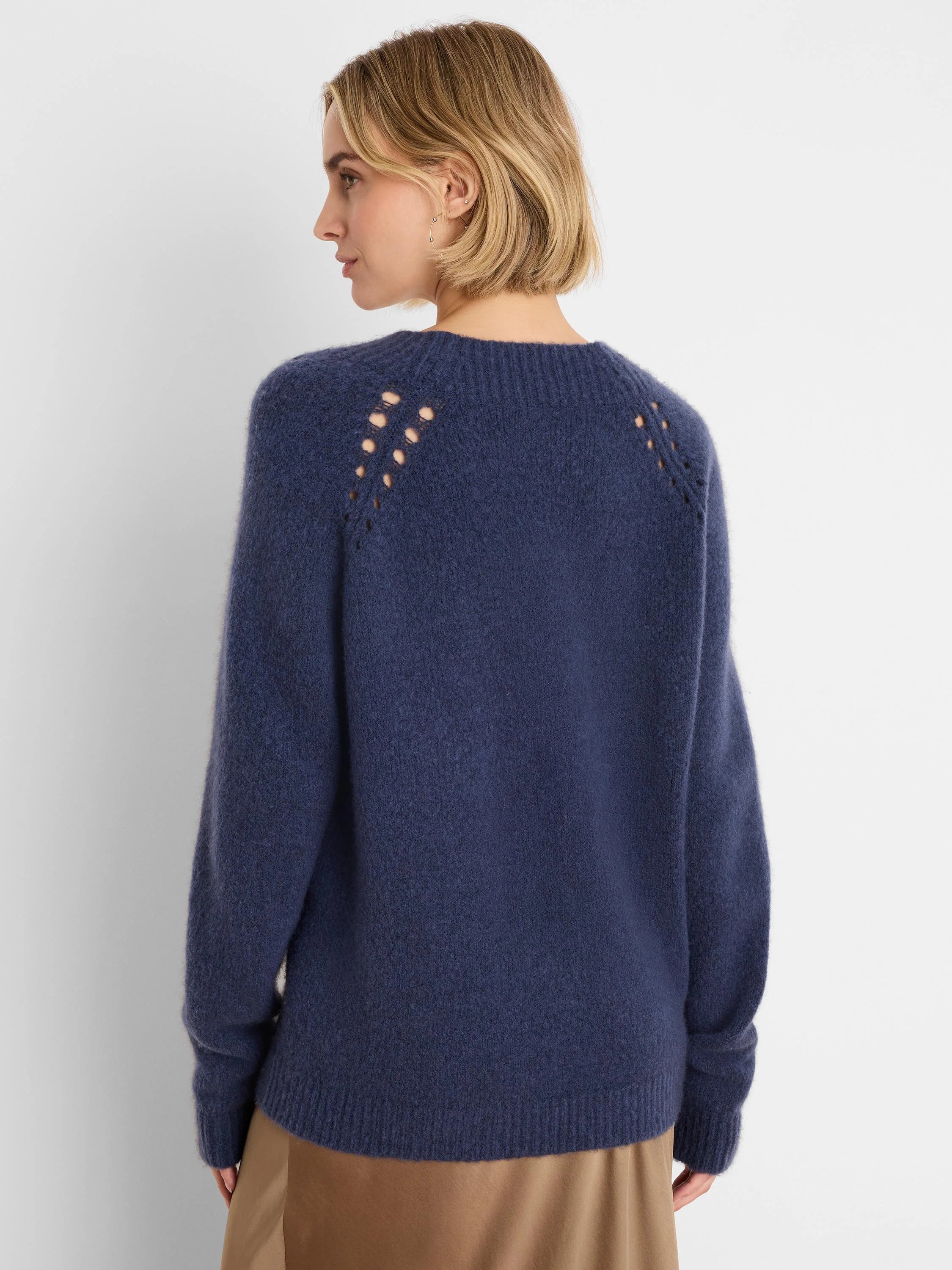 Deep blue fuzzy knit sweater with shoulder cutouts, seen from the back on a model.