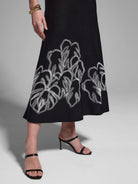 Black midi dress with white embroidered leaf pattern at hem.