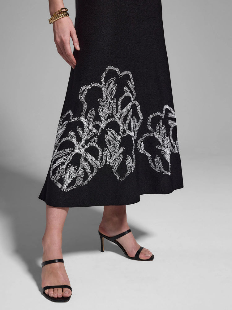 Black midi dress with white embroidered leaf pattern at hem.