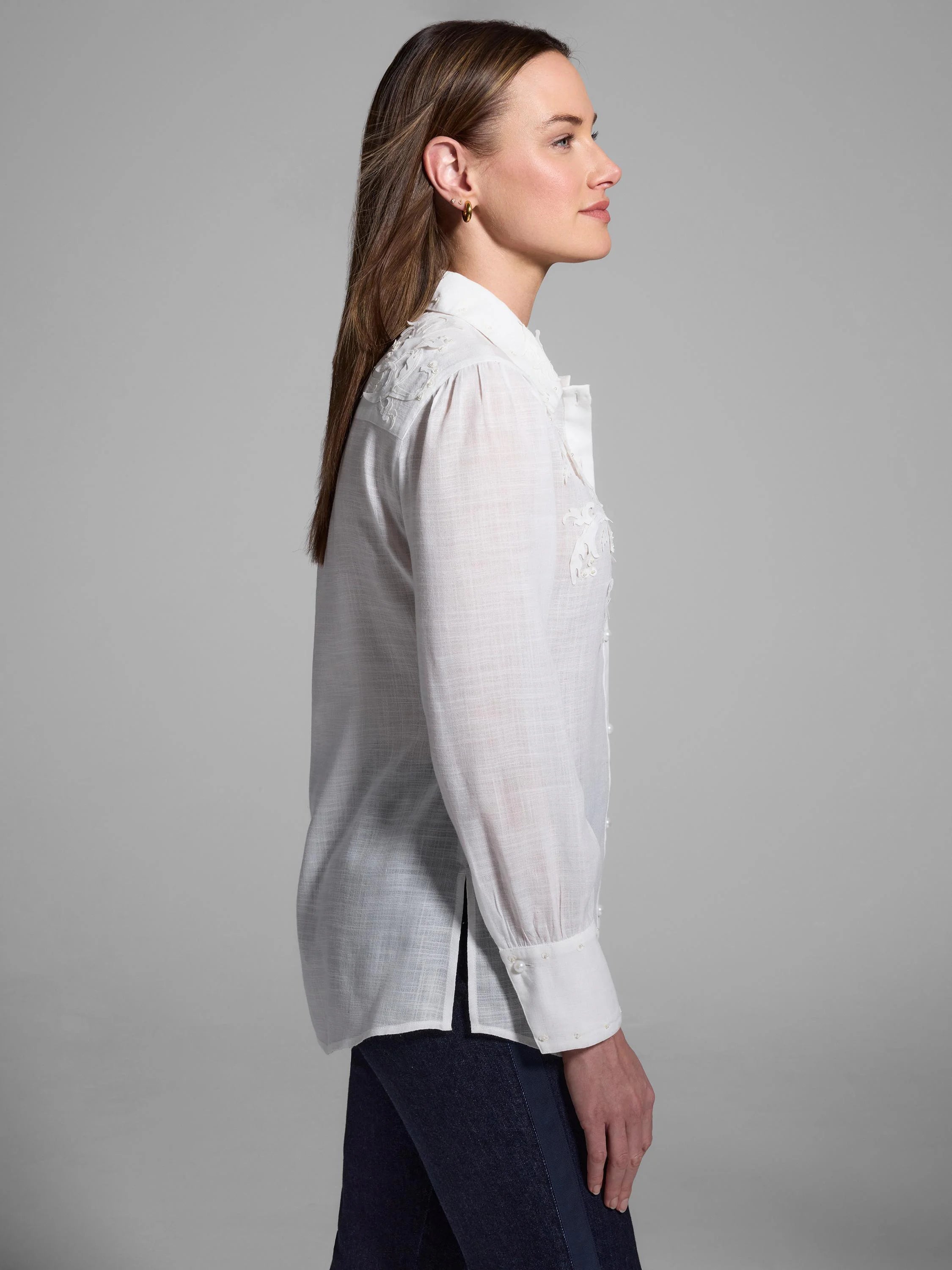 Off-white collared shirt with long sleeves and pearl embellishments.  Side view shows textured fabric.