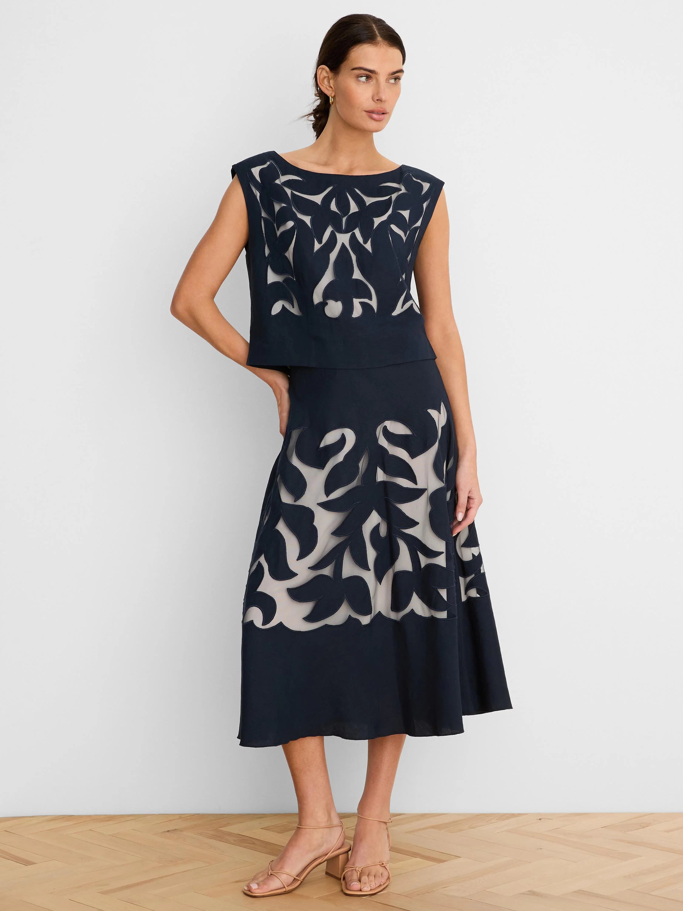 Dark navy sleeveless top with intricate organic cut-outs revealing a light lining. Worn with matching midi skirt.