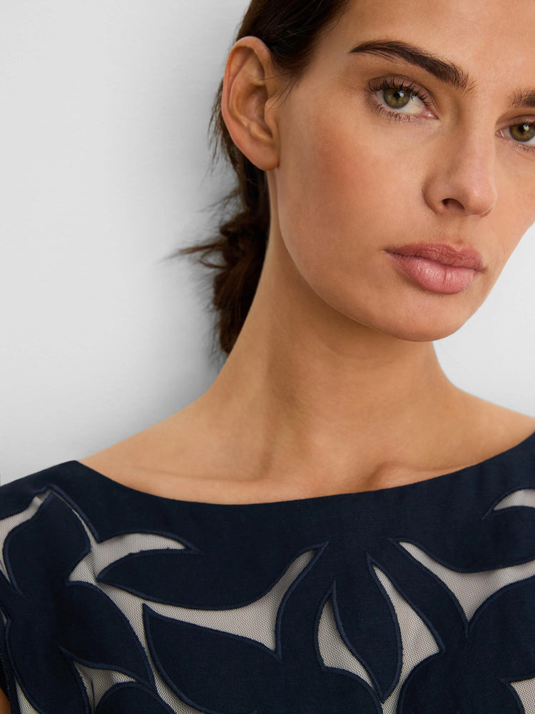 Dark blue linen cut-out top with a wide neckline, showing a beige sheer leaf pattern underneath.