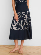 Dark navy A-line skirt with leaf pattern cutouts revealing a light beige layer. Ankle length.