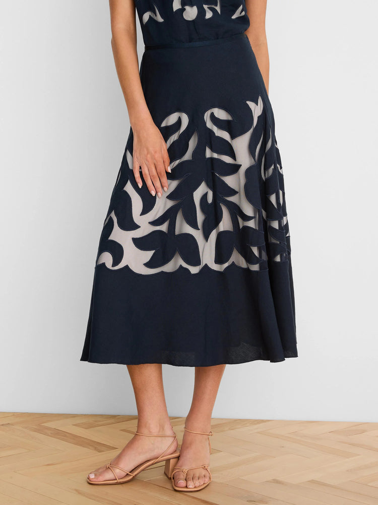 Dark navy A-line skirt with leaf pattern cutouts revealing a light beige layer. Ankle length.
