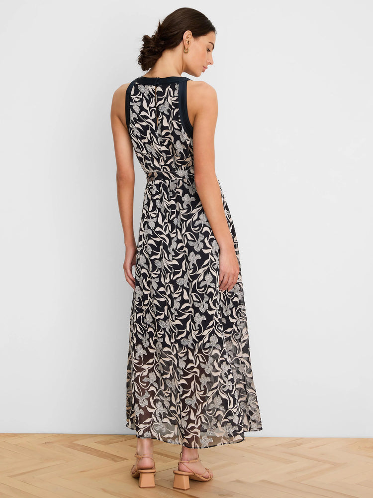 Dark maxi dress with creamy floral burnout pattern, sleeveless, high neck, and tied waist, viewed from the back.