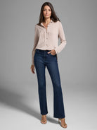 Beige long-sleeve collared sweater with subtle texture, worn with dark wash jeans.