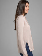 Beige long-sleeve collared sweater with side slits.  The sweater is shown on a model.