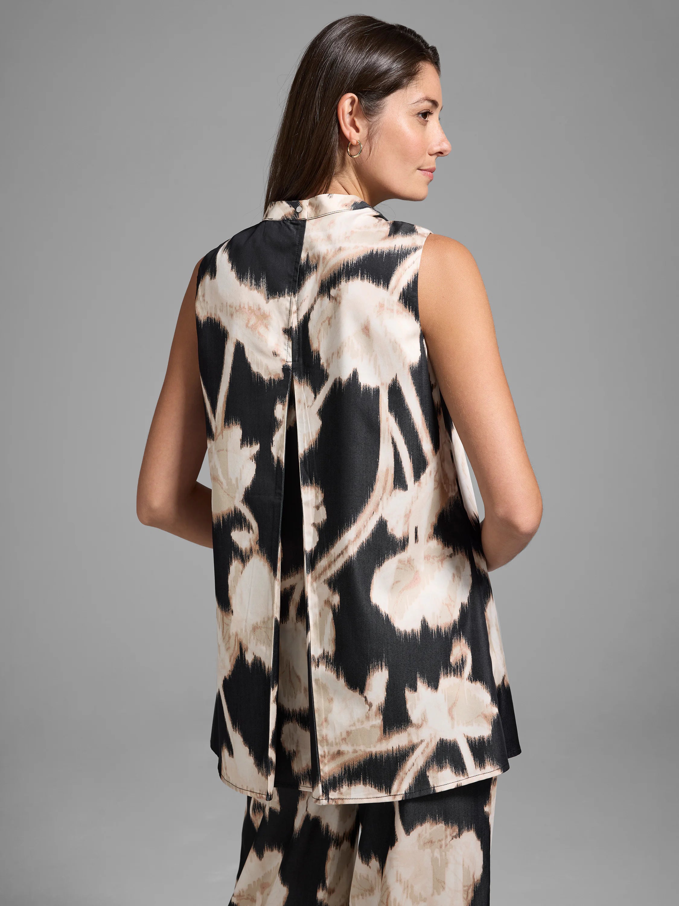 Black sleeveless top with beige floral print, back pleat detail.