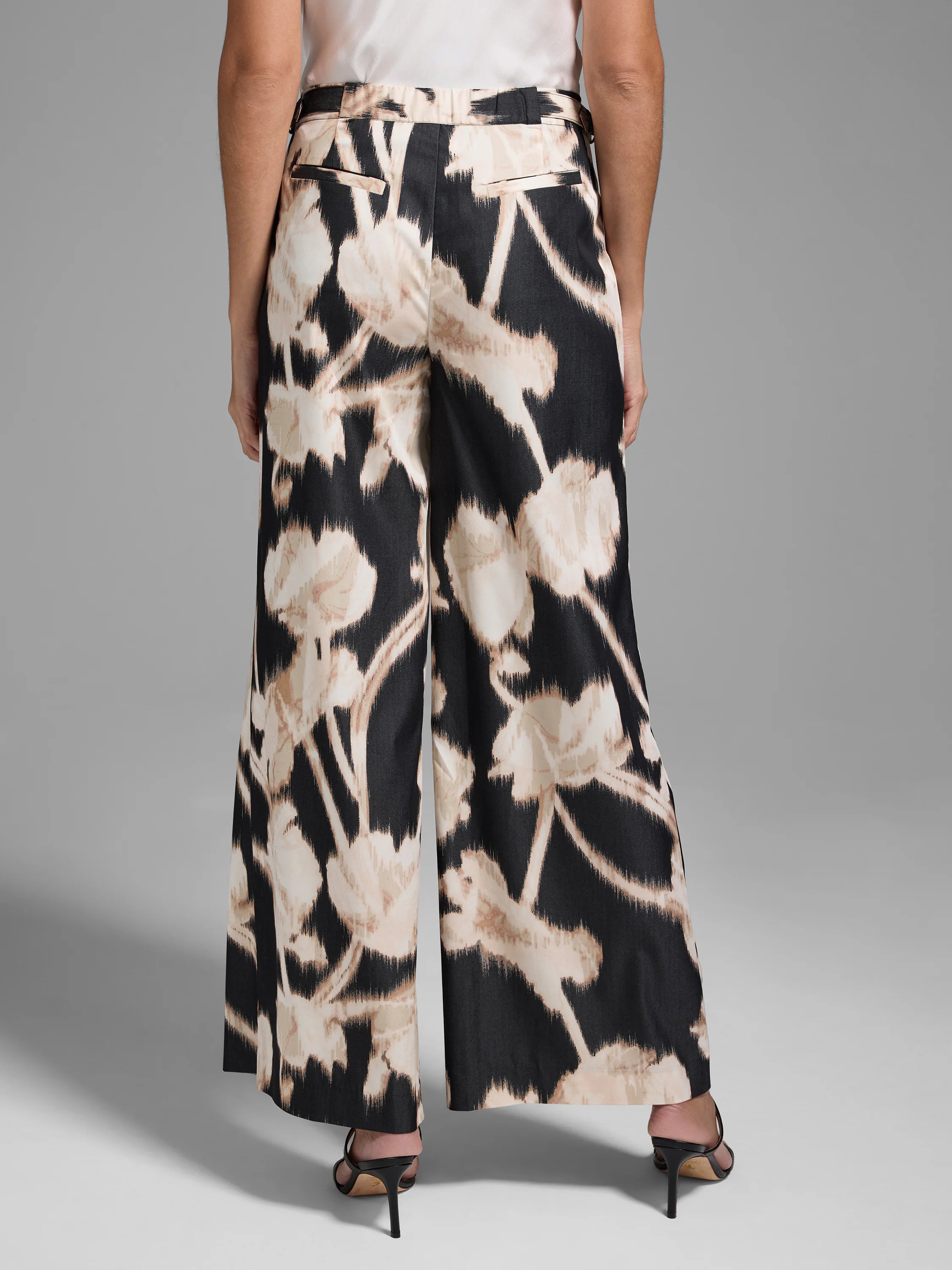 Black wide-leg pants with a beige floral print.  The flowers are abstract and slightly blurred.