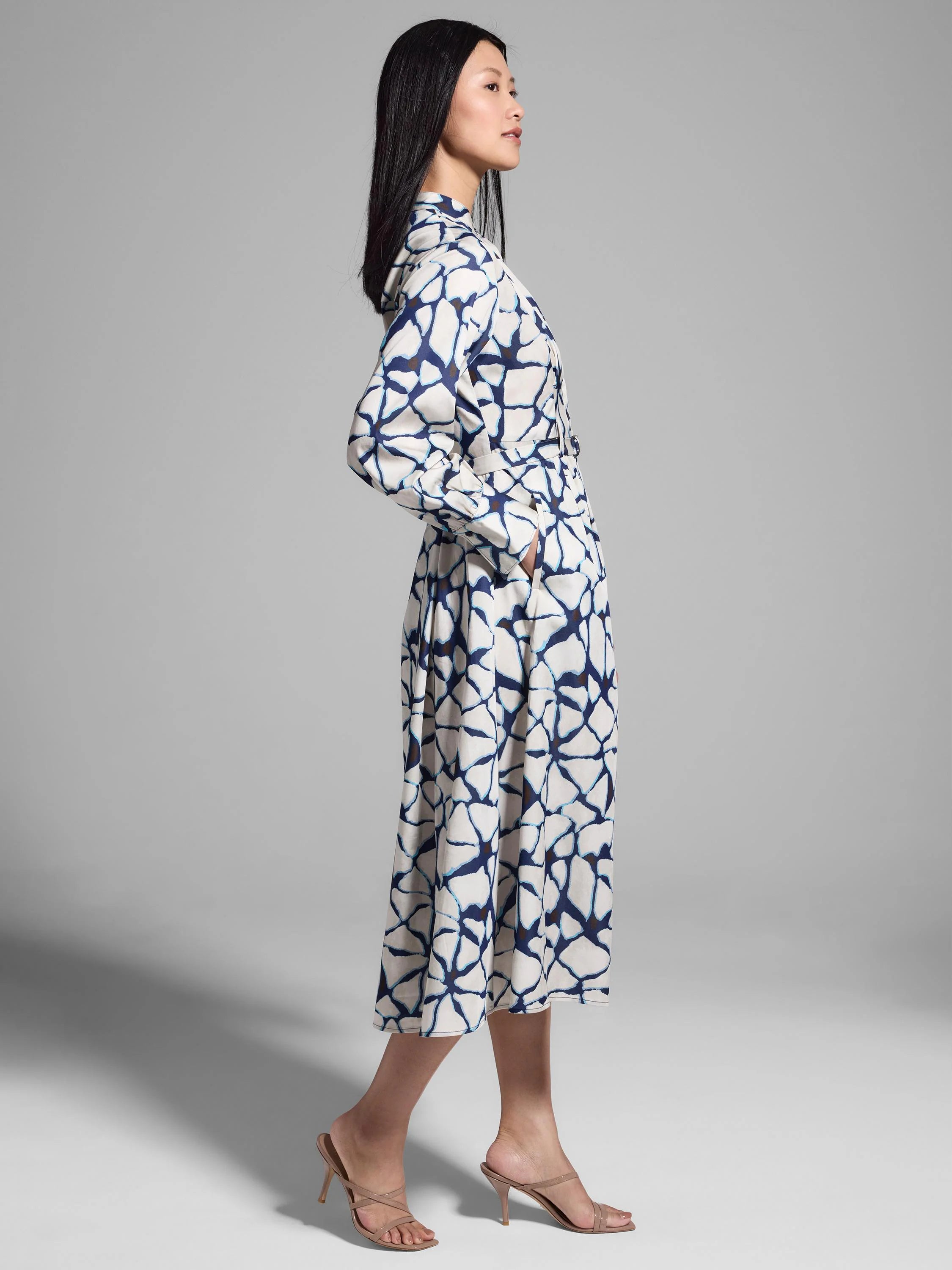 Off-white midi shirt dress with a navy blue and white fractured line pattern, long sleeves, and a belted waist.
