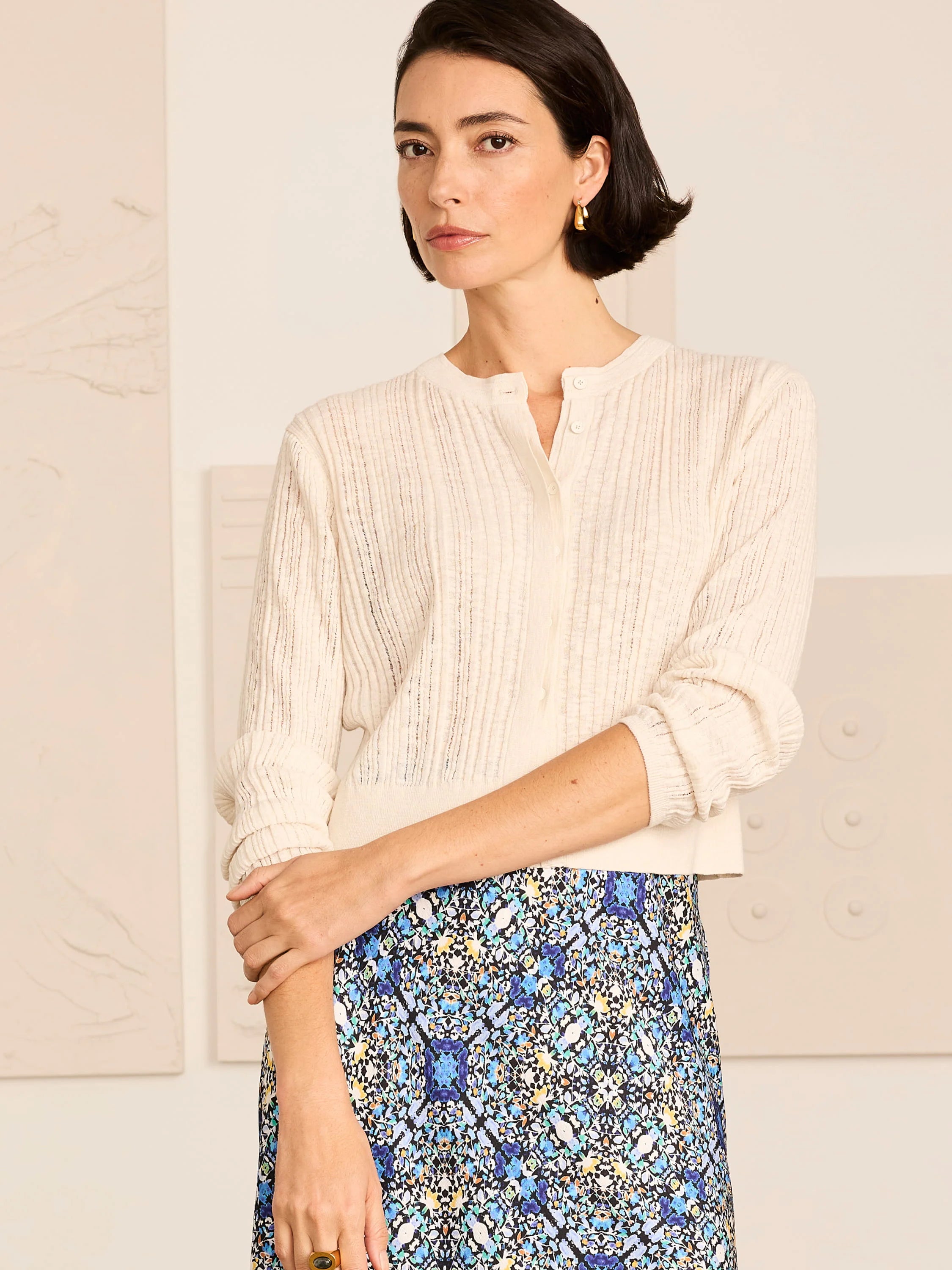 Cream pointelle knit cardigan with long sleeves and front buttons.