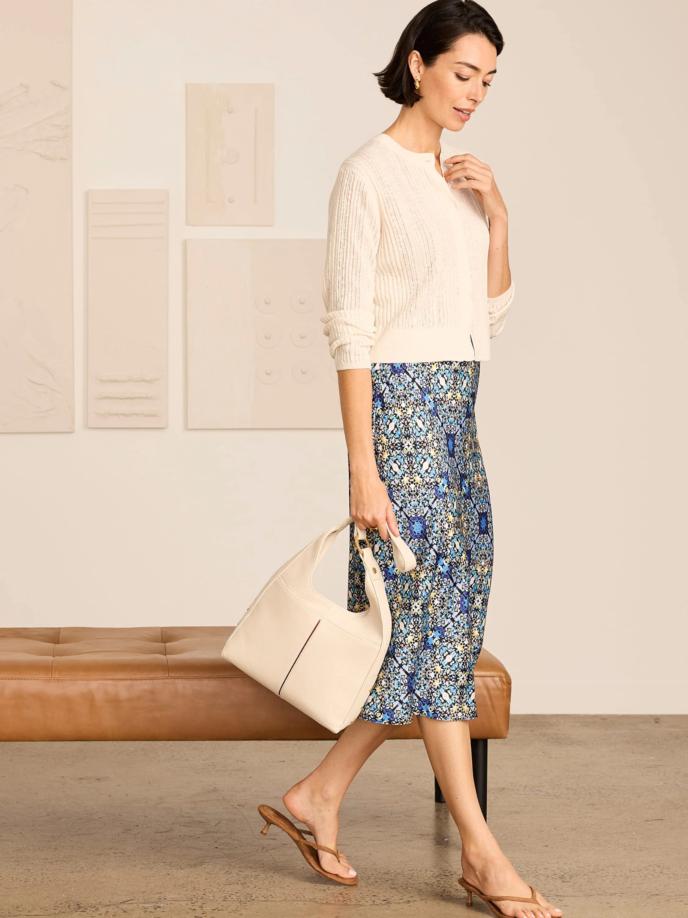 Off-white pointelle stitch cardigan. Features button-front closure, ribbed cuffs/hem, and a cropped fit.