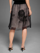Black sheer embroidered mesh skirt with abstract black designs over a tan lining. Midi length.