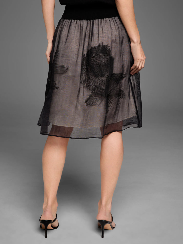 Black sheer embroidered mesh skirt with abstract black designs over a tan lining. Midi length.