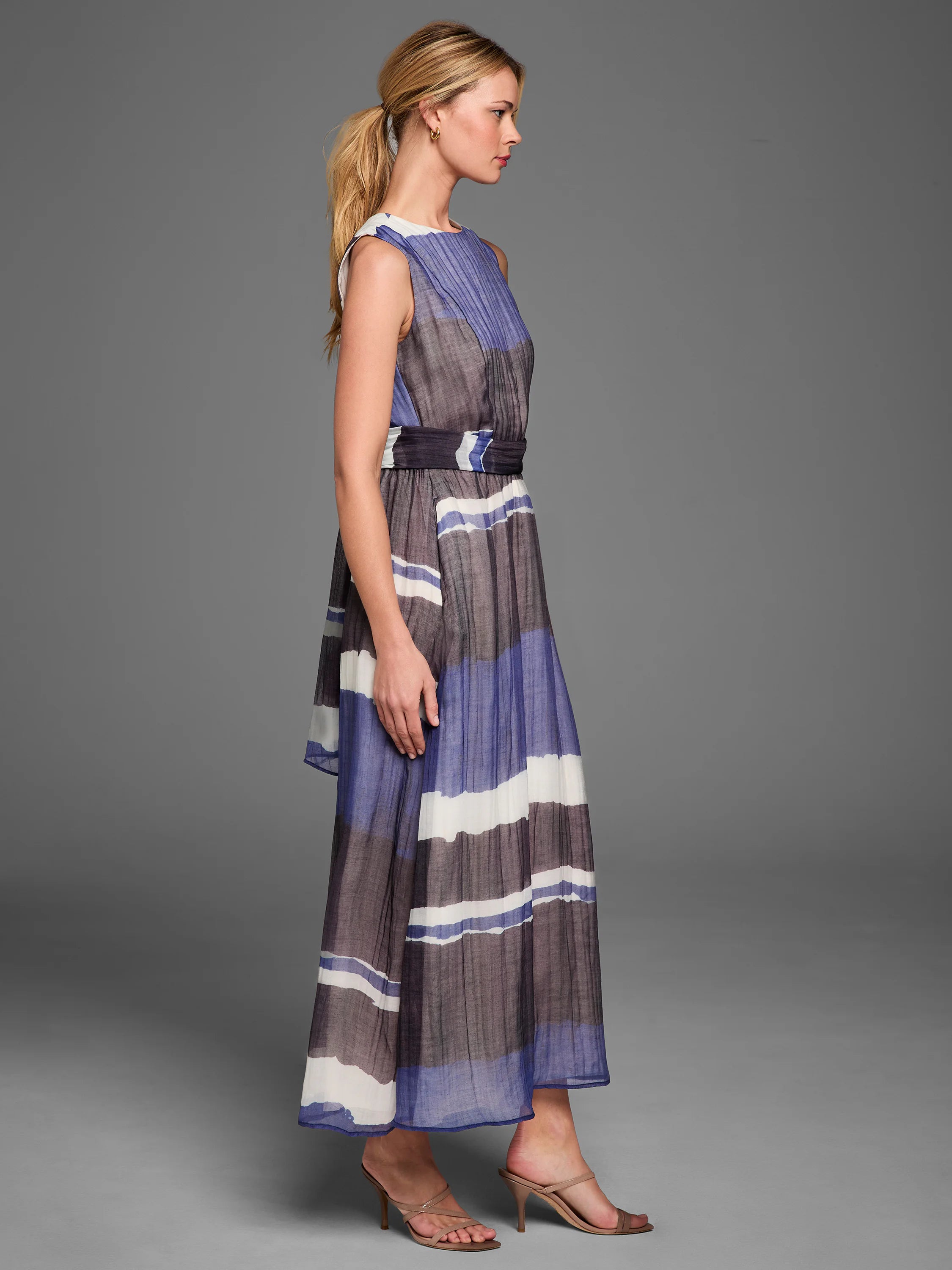 Sleeveless maxi dress with horizontal blue, white, and dark gray stripes, featuring a pleated bodice and waist sash.