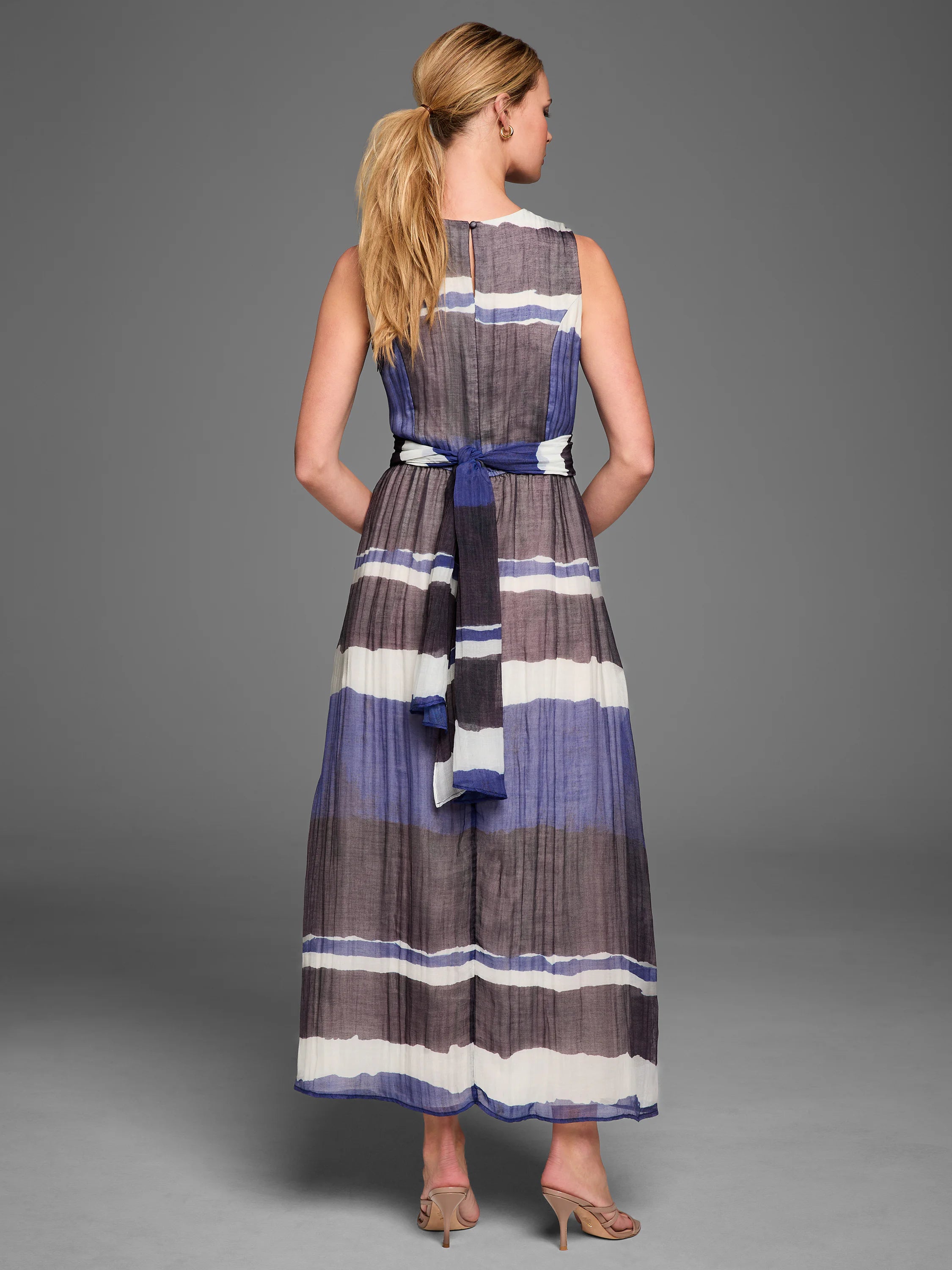 Sleeveless maxi dress with horizontal white, periwinkle blue, and dark gray stripes, tied at the back with a matching belt.