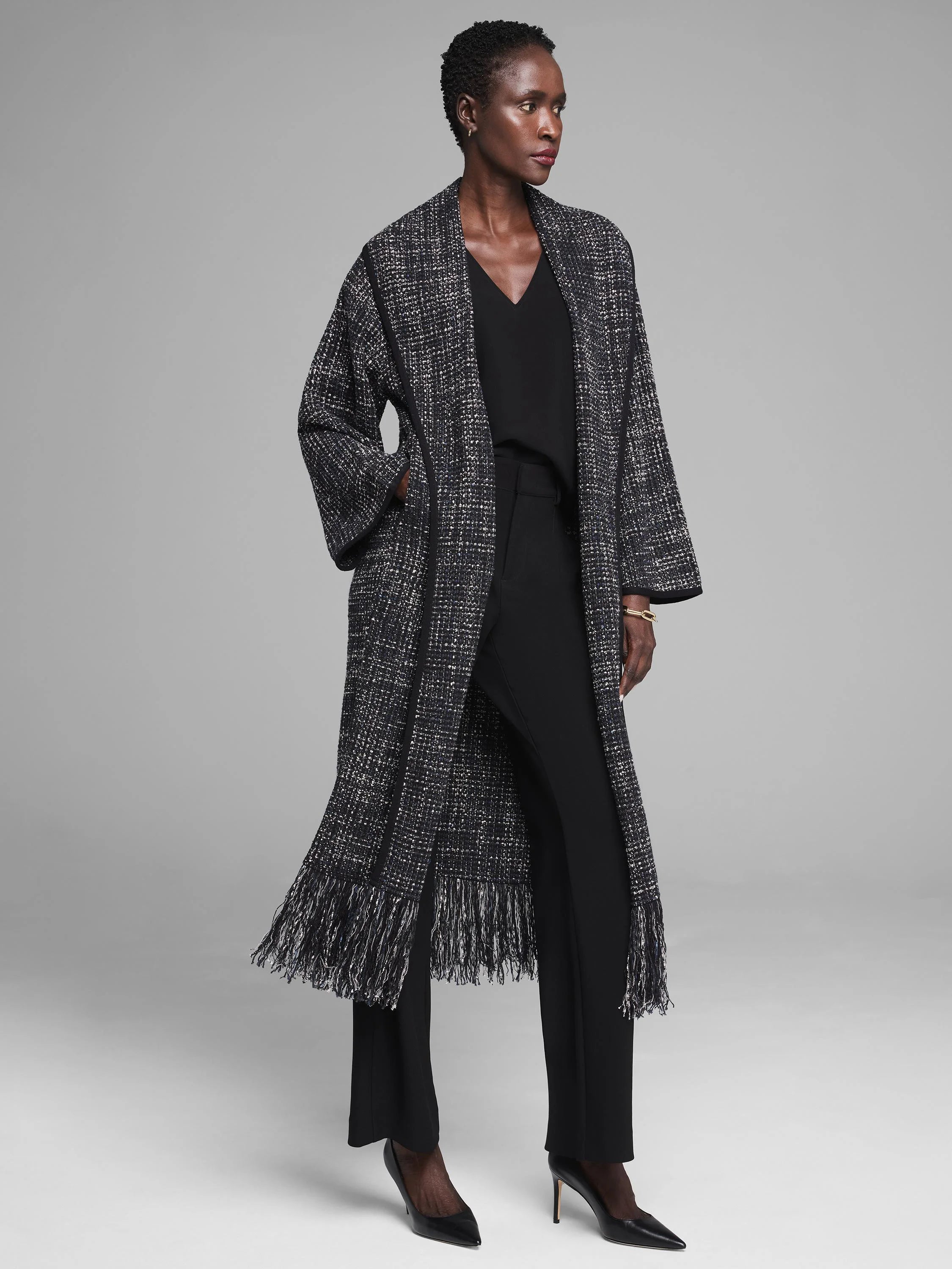 Black V-neck tank shown on model, under a long, textured black and white coat.