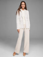 Off-white blazer with silver studs along the lapels, pockets, and sleeves.  The blazer is shown on a model.