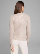 Beige knit sweater with subtle lighter floral pattern, long sleeves, and slightly puffed shoulders.