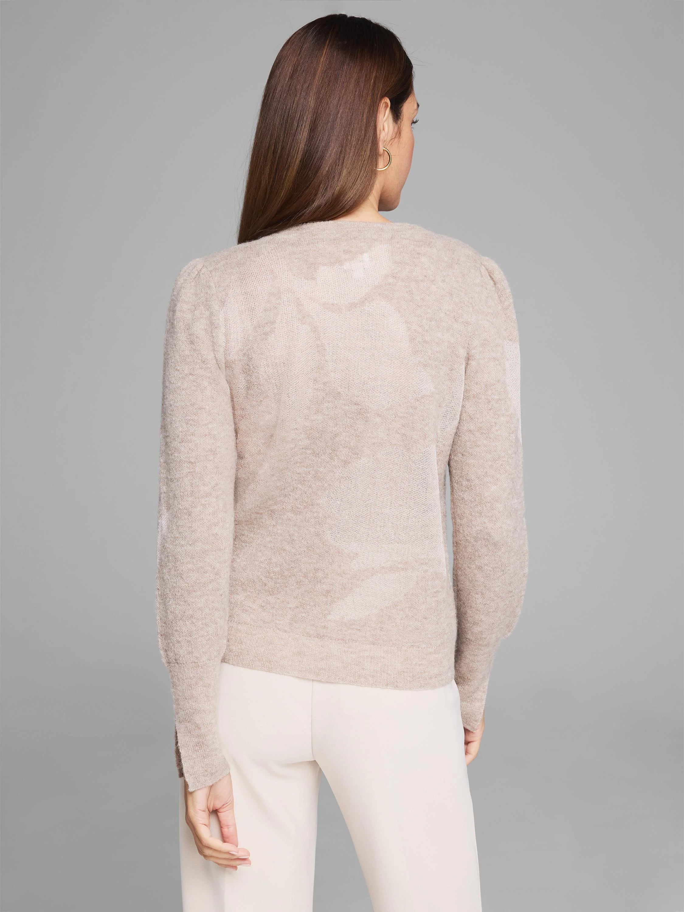 Beige knit sweater with subtle lighter floral pattern, long sleeves, and slightly puffed shoulders.