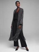 Long black, white, and gold tweed-texture jacket with fringe along the hem and high side slits.