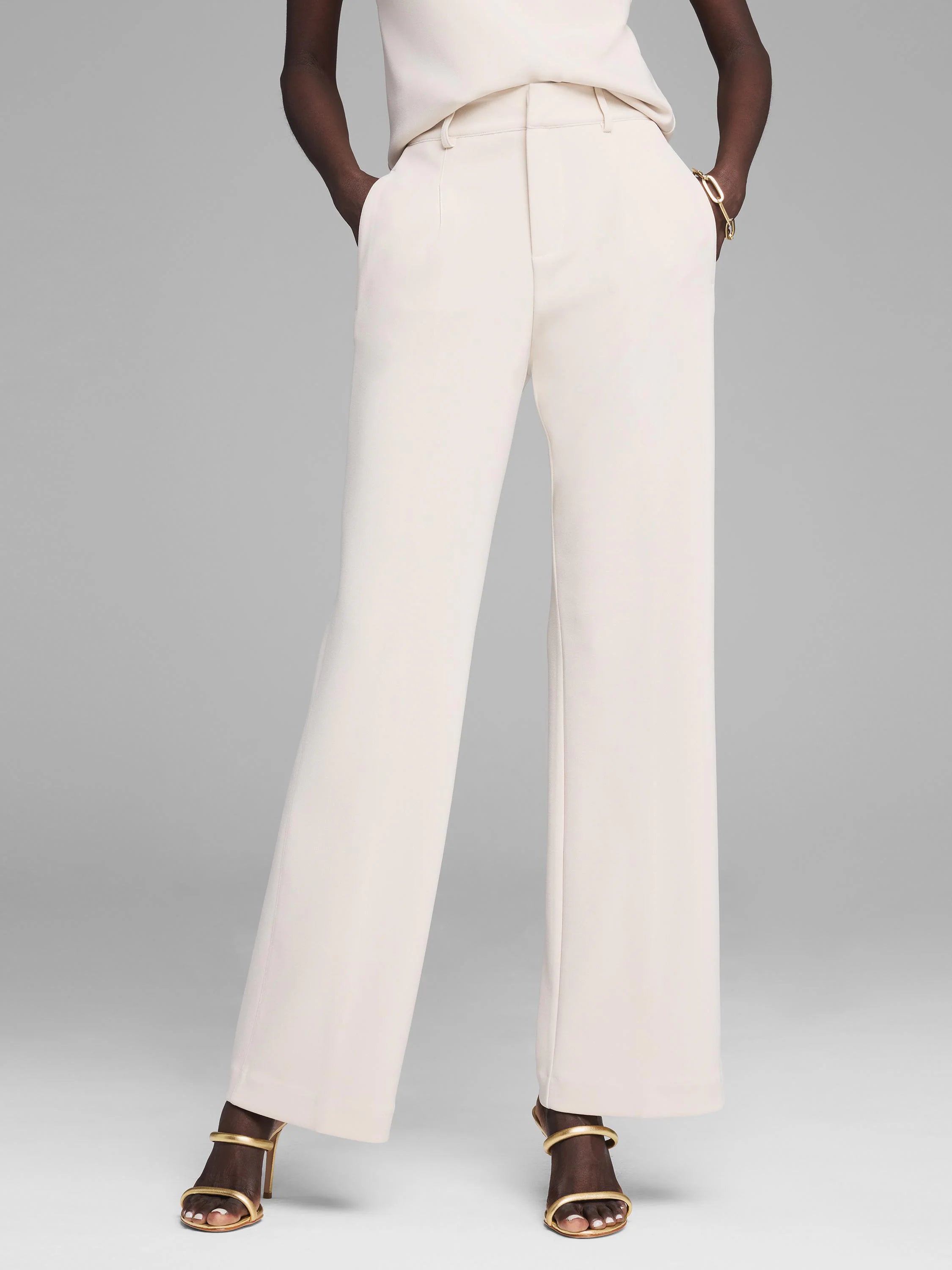 Cream wide-leg trousers with a flat front, belt loops, and center leg creases, worn by a model.