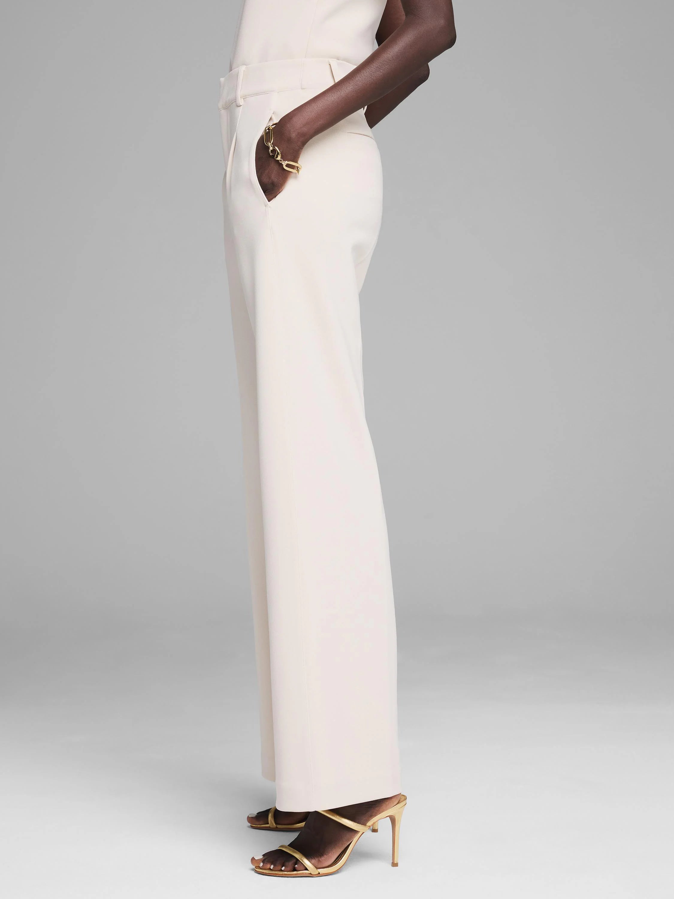 Cream wide-leg trousers, smooth scuba knit fabric. Model's hand is in a hip pocket, showing the full length.
