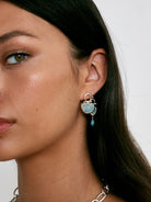 Silver-toned earrings with a light blue, semicircular aquamarine stone and a dangling dark blue teardrop.