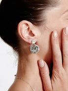 Silver hammered drop earring on an ear, with two irregular, organic-shaped pieces.