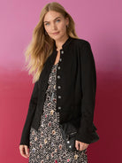 Black knit jacket with a stand-up collar and silver-toned decorative buttons.