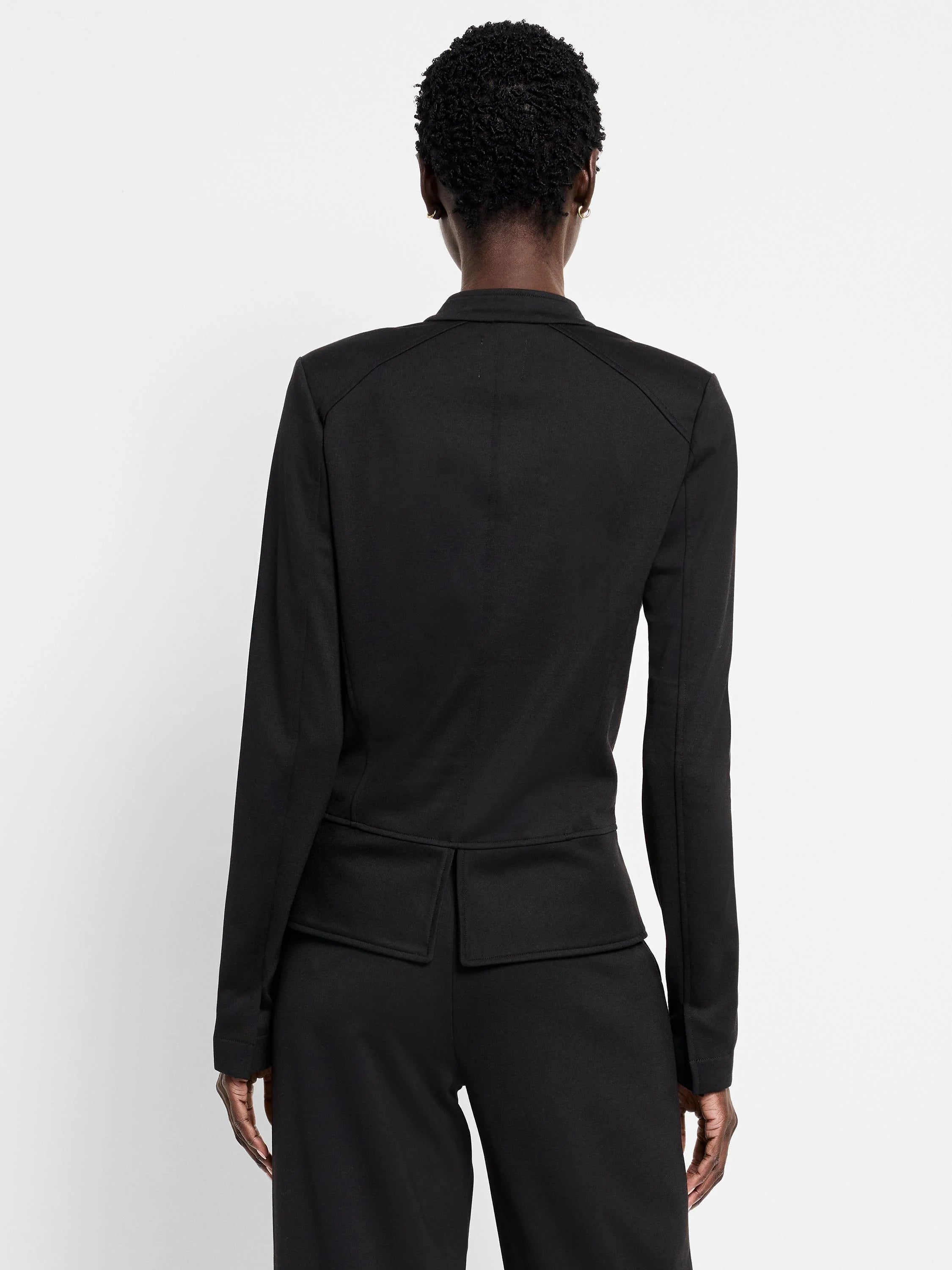 Black knit jacket, back view. Structured shoulders, horizontal seam above two back vents.