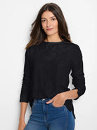Black long-sleeve tee with a subtle, all-over lace knit texture and wide neckline, worn by a woman.