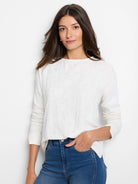 Model in a cream, long-sleeve, boat-neck tee with a subtle all-over lace knit texture.