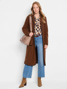 Long brown teddy coat with fuzzy texture and black trim along its edges.