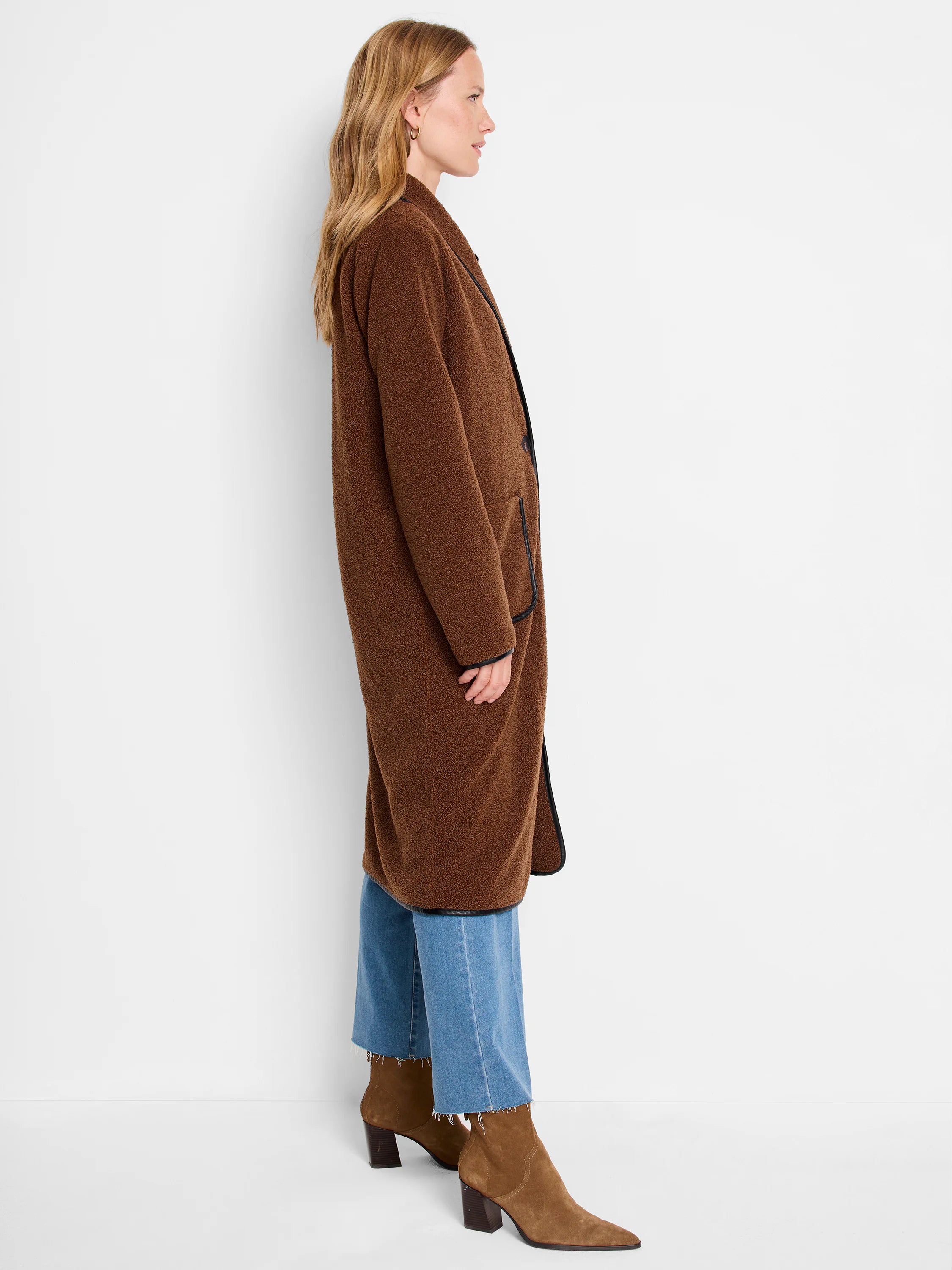 Brown fuzzy teddy coat with black trim along the lapels, pockets, and hem.