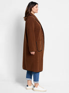 Brown fuzzy coat with black trim on lapels, patch pockets, & hem. Long length, open front.