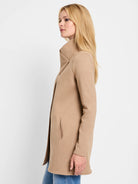 Tan mid-length jacket with a high, wrap collar fastened by one button and discreet vertical pockets.