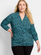 Teal leopard print top with black, blue, and yellow spots. Features a notched V-neck and long ruched sleeves.