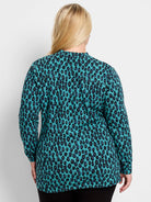 Teal long-sleeved top with abstract black, purple, and yellow pebble-like spots.