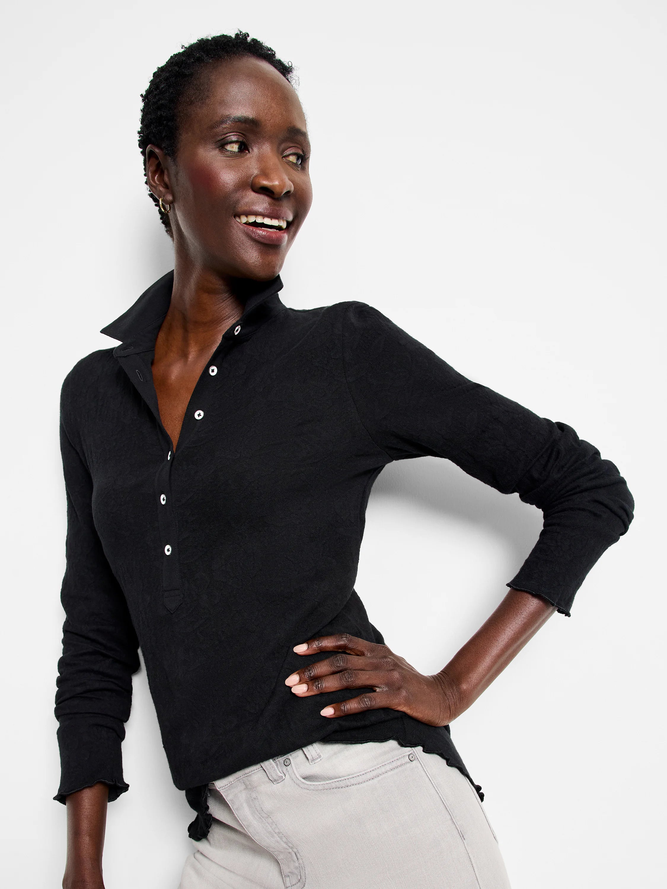 Black lace knit collared top with white buttons, long sleeves, and ruffled cuffs/hem.