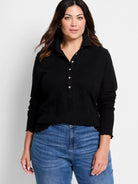Black lace knit collared top with a Henley placket, white buttons, long sleeves, and ruffled trim.