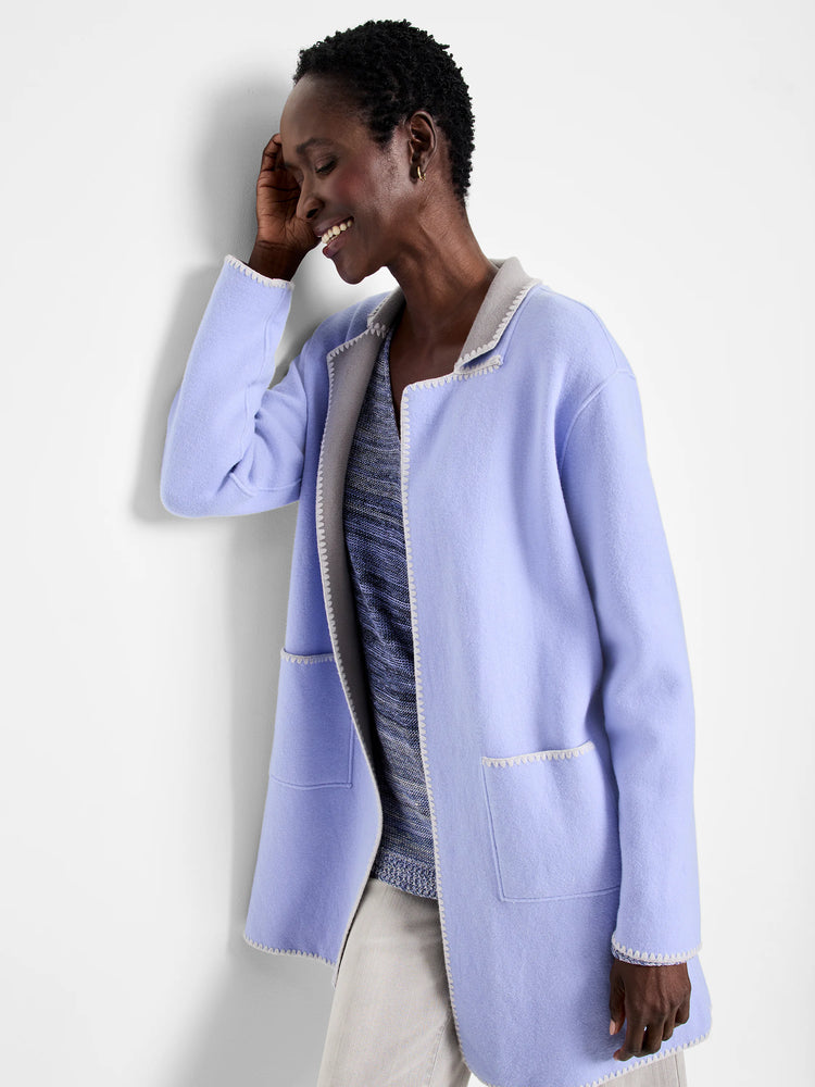 Periwinkle knit jacket with light grey reversible side and white zig-zag edge stitching, worn open.