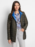 Reversible quilted puffer jacket: olive green side with visible bright blue collar lining, snap buttons.