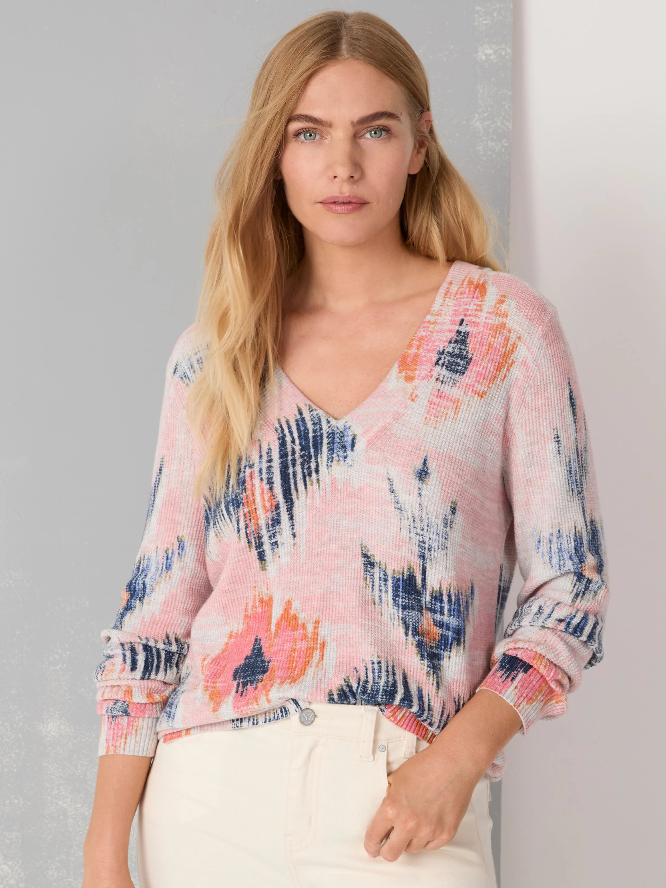 Pink waffle V-neck sweater with abstract patterns in dark blue, orange, and white.