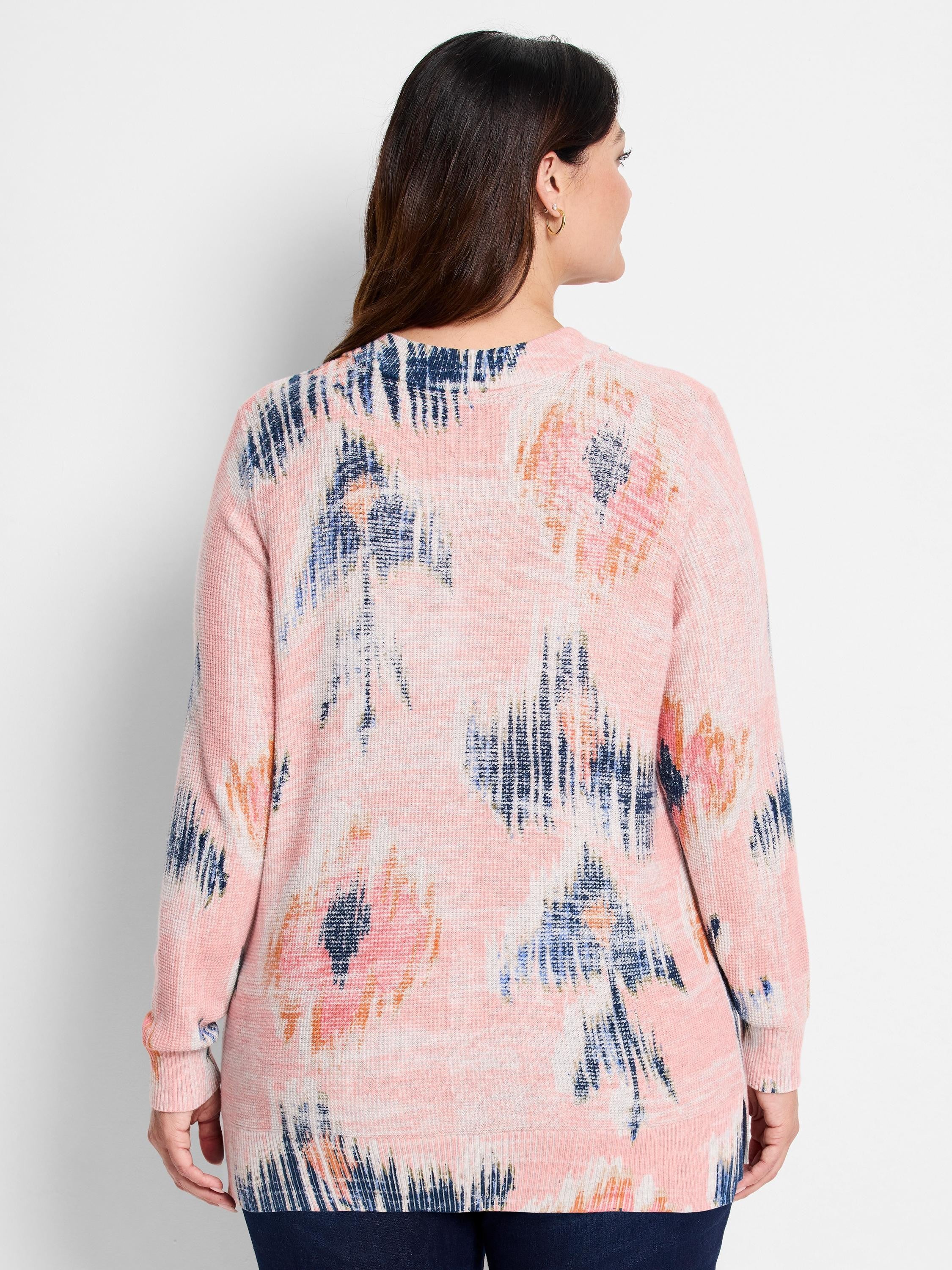 Light pink waffle stitch sweater with an abstract pattern in dark blue, light blue, and orange.