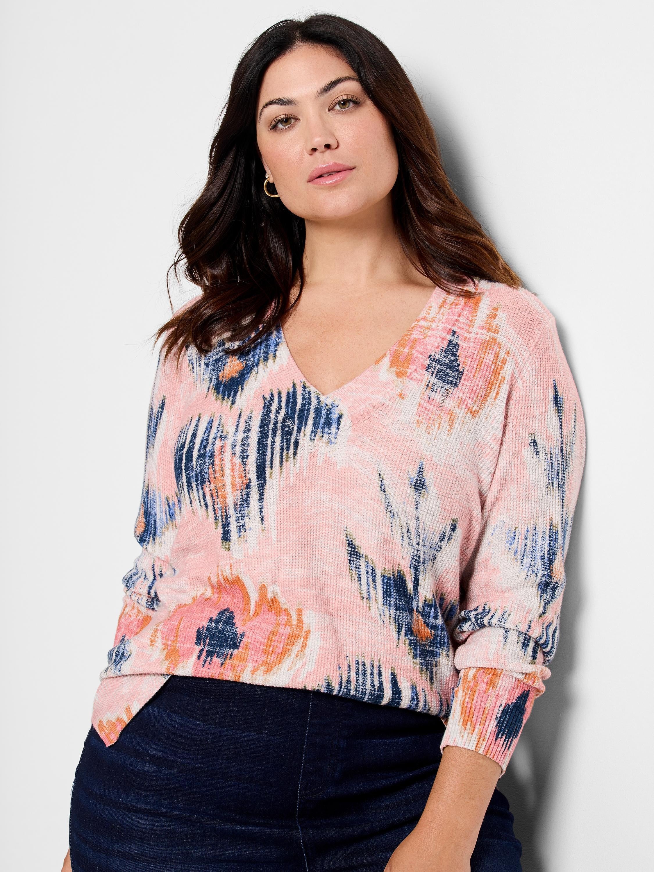 Pink V-neck sweater with abstract blue and orange pattern.