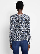 White sweater with a tossed paisley pattern in black and blue, worn by a model viewed from the back.